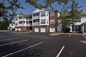 A parking lot in front of a two story apartment building.